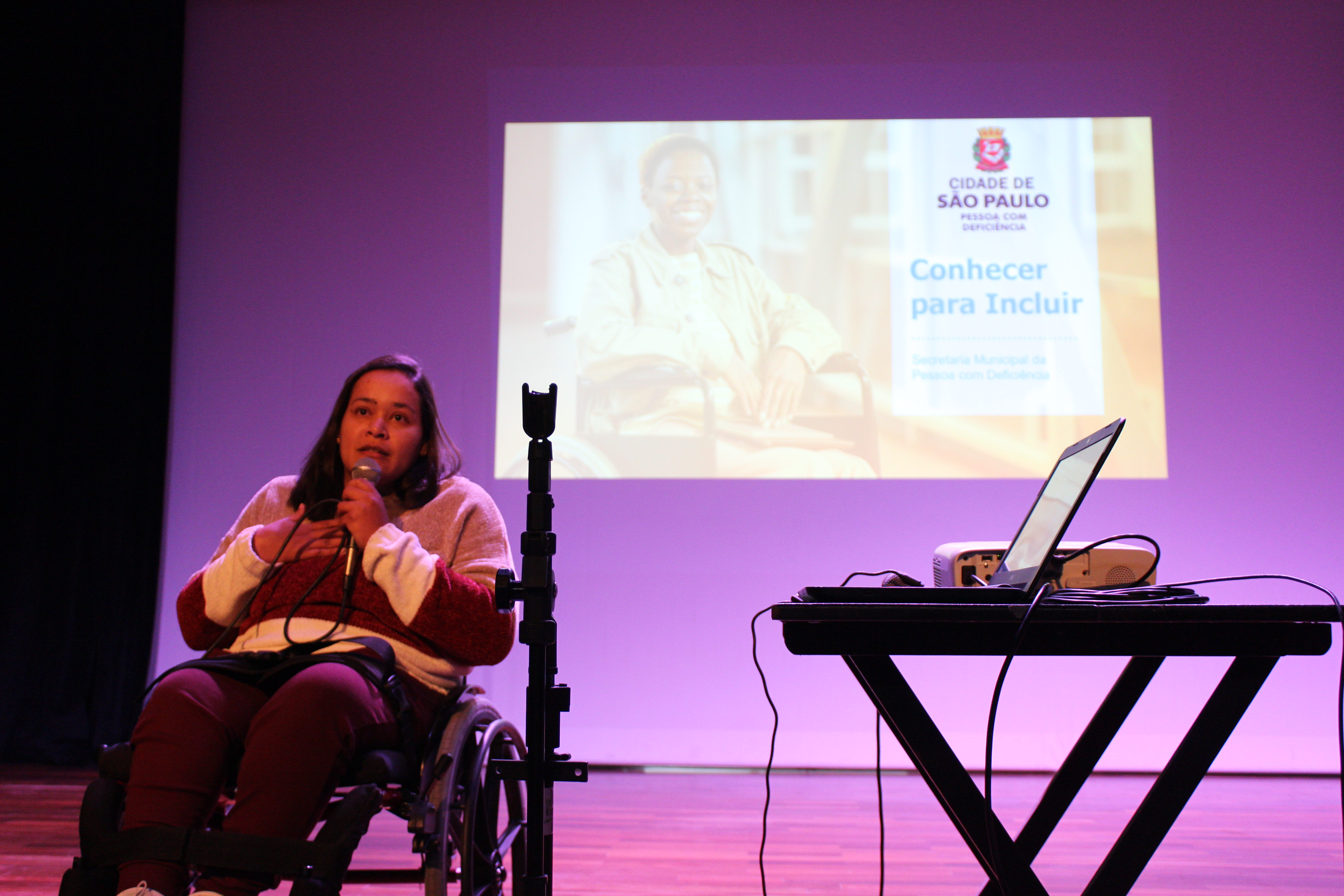 No CEU Carrão, a assessora técnica da SMPED Myrna ministra o curso, do palco. Telão ao fundo com a apresentação.