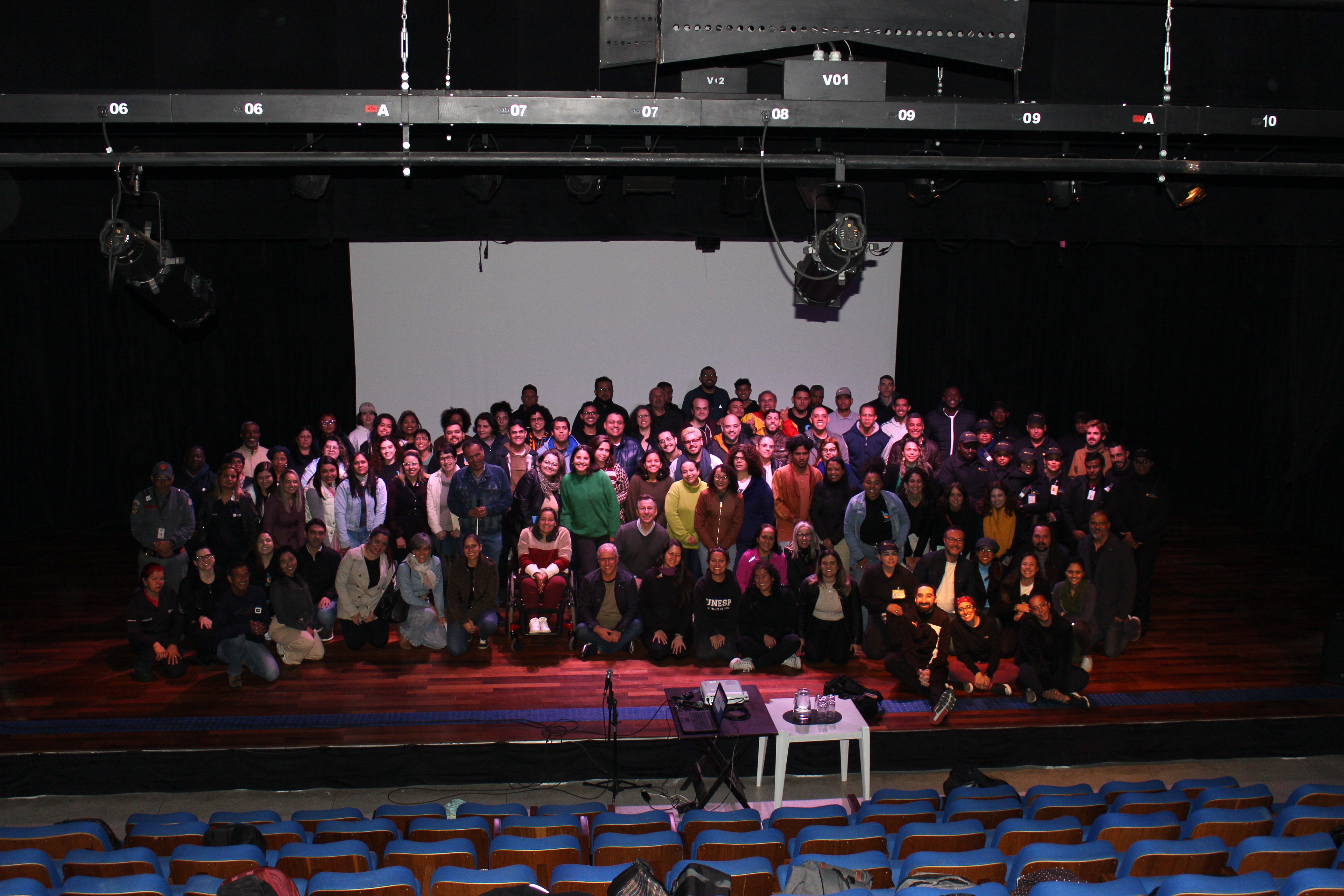 Imagem dos alunos do curso, assessores técnicos da SMPED, chefe de gabinete Flávio Fenólio no palco do auditório. 