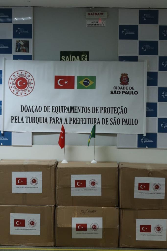 Foto de caixas da doação de máscaras com as bandeiras da Turquia e do Brasil. 
