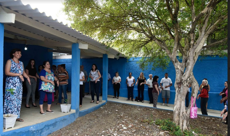  Usuários do Centro de Práticas Naturais fazem atividade na área externa. Há uma árvore no jardim.