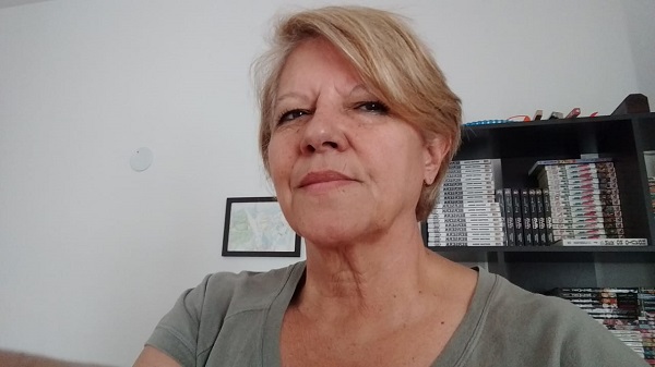 #PraCegoVer: Rita fez uma selfie. Ela é loira, tem cabelo curto e está numa sala com uma estante de livros ao fundo.