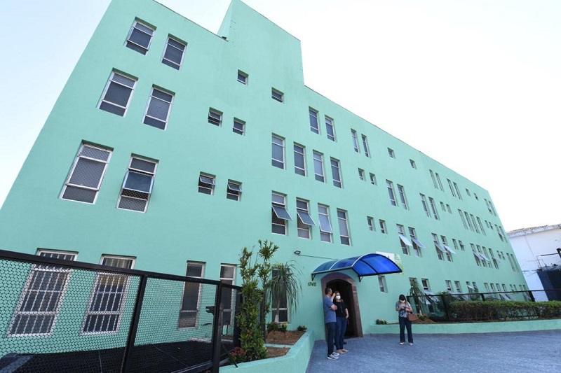 Fachada do prédio do Serviço Integrado de Acolhida Terapêutica (SIAT) num tom claro de verde com três pessoas em frente