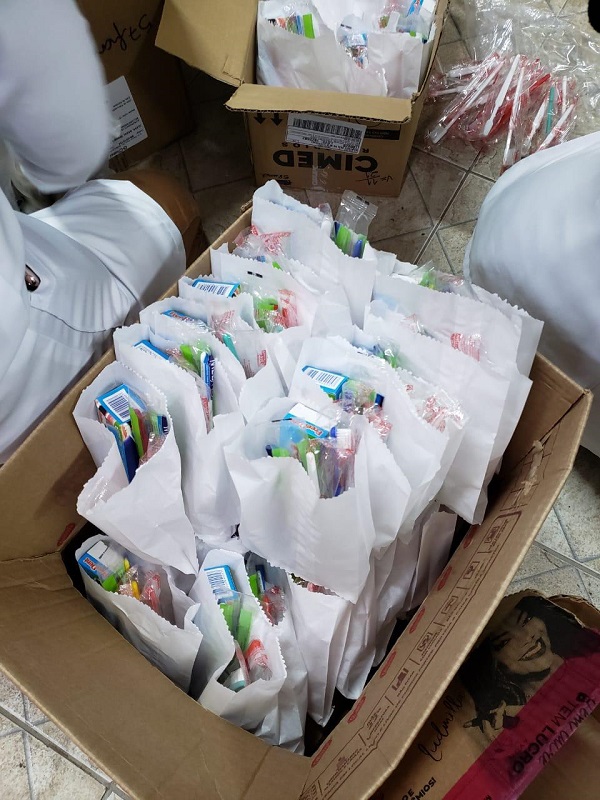 #PraCegoVer: Fotografia dos agentes de Saúde entregando kits de higiene e cestas básicas