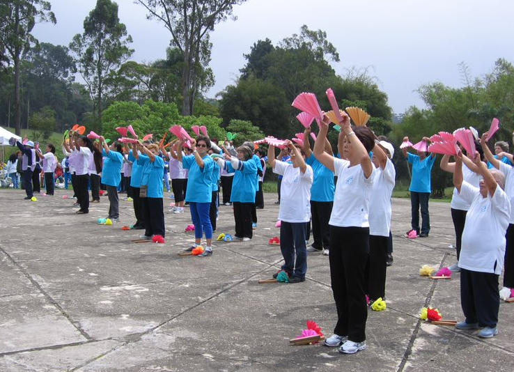 Um grupo de pessoas está no Parque do Carmo segurando leques coloridos