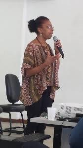 Foto tirada da Edna Muniz em uma palestra, falando no microfone.