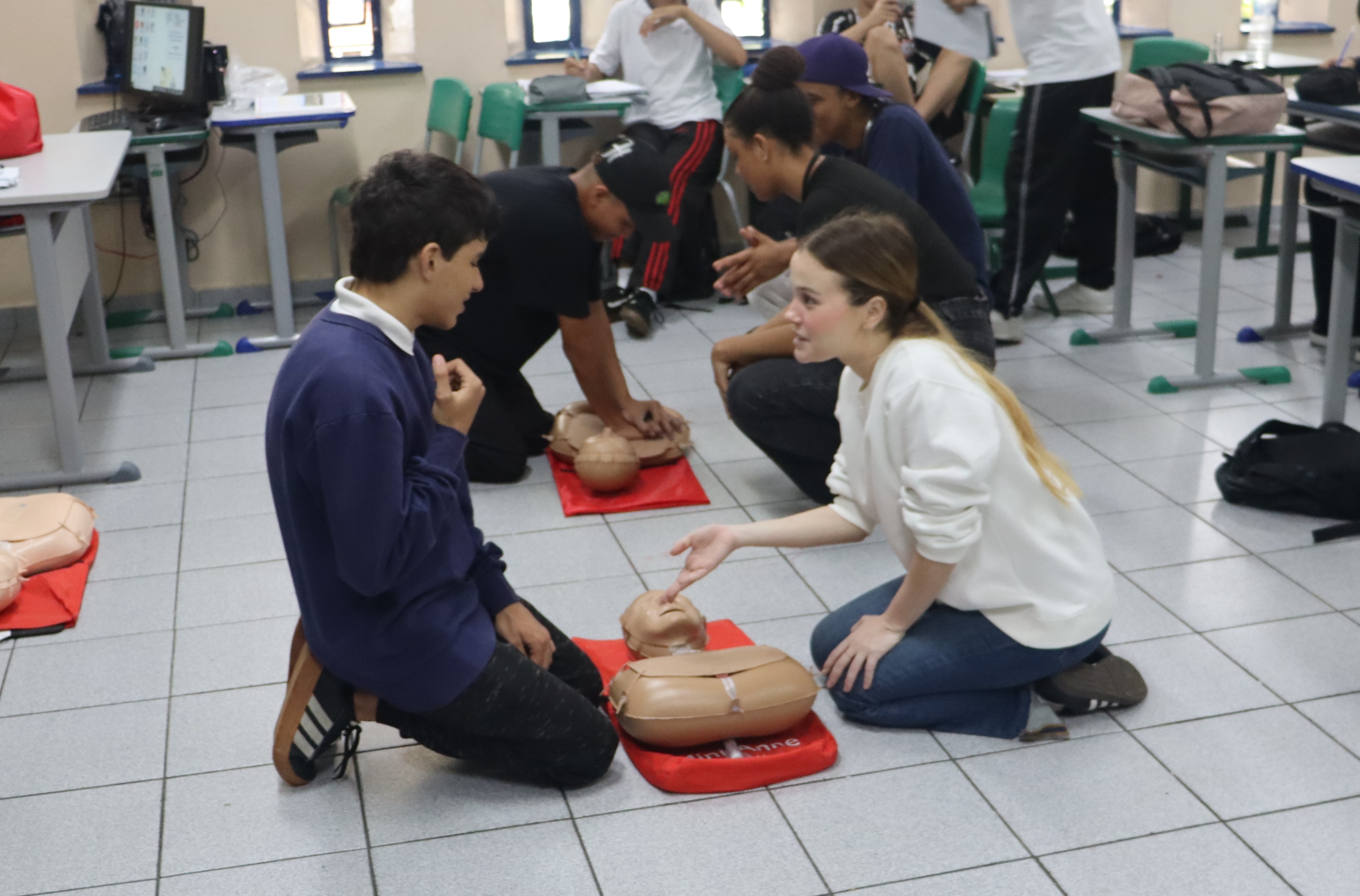 Crianças realizando manobra de RCP junto as instrutoras