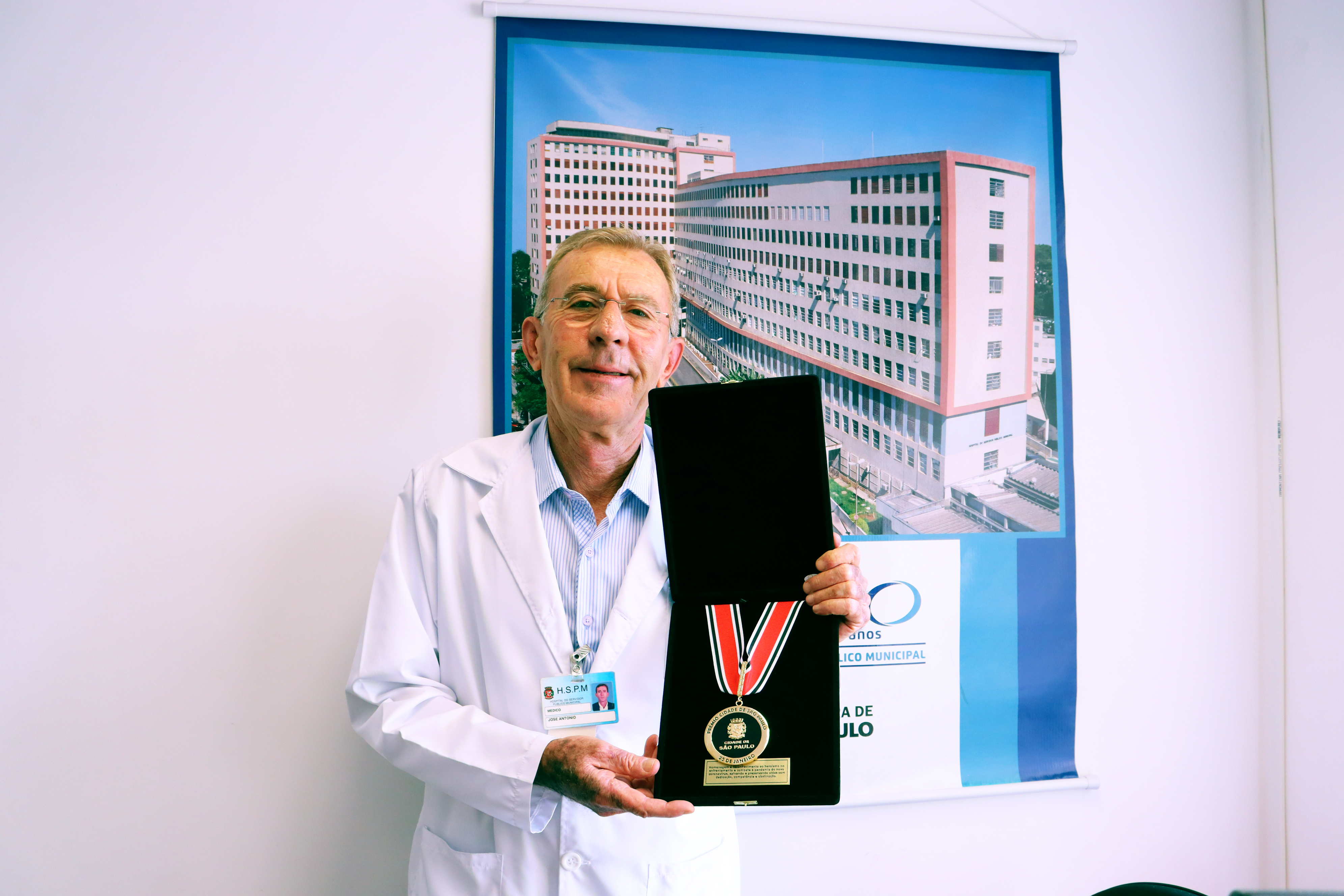 Foto do dr. Volpiani sorridente mostrando a medalha