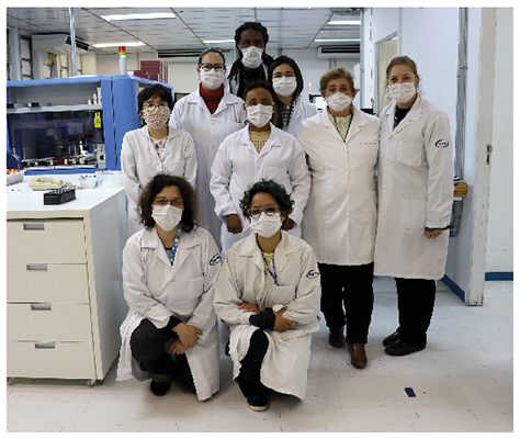 Foto de parte da equipe de biólogos no laboratório do HSPM, nove pessoas, sendo um homem, e todos de jaleco e máscara 