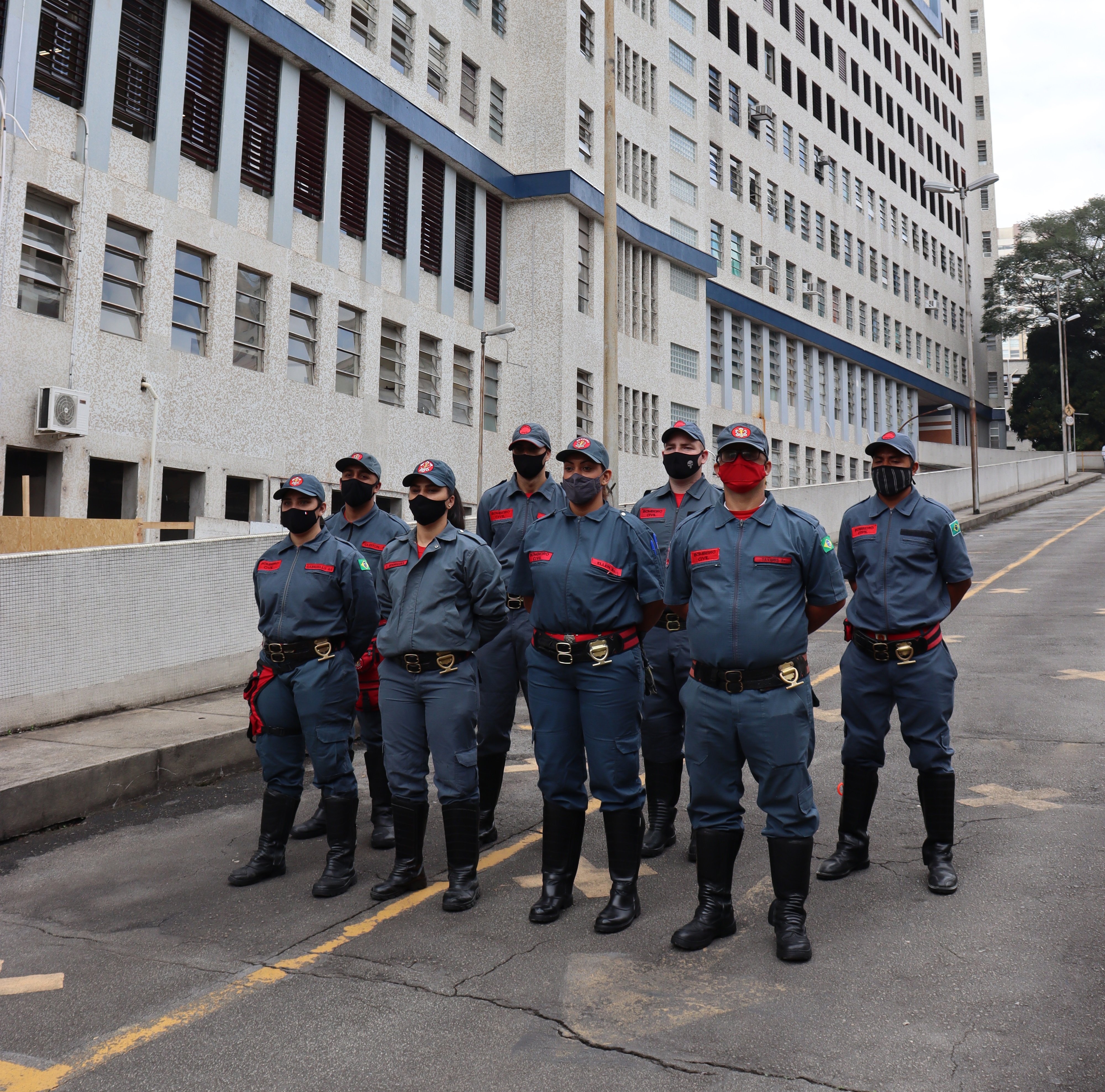 foto com a equipe de oito bombeiros uniformizados, parados com as mãos para trás em frente á rampa do hospital. 