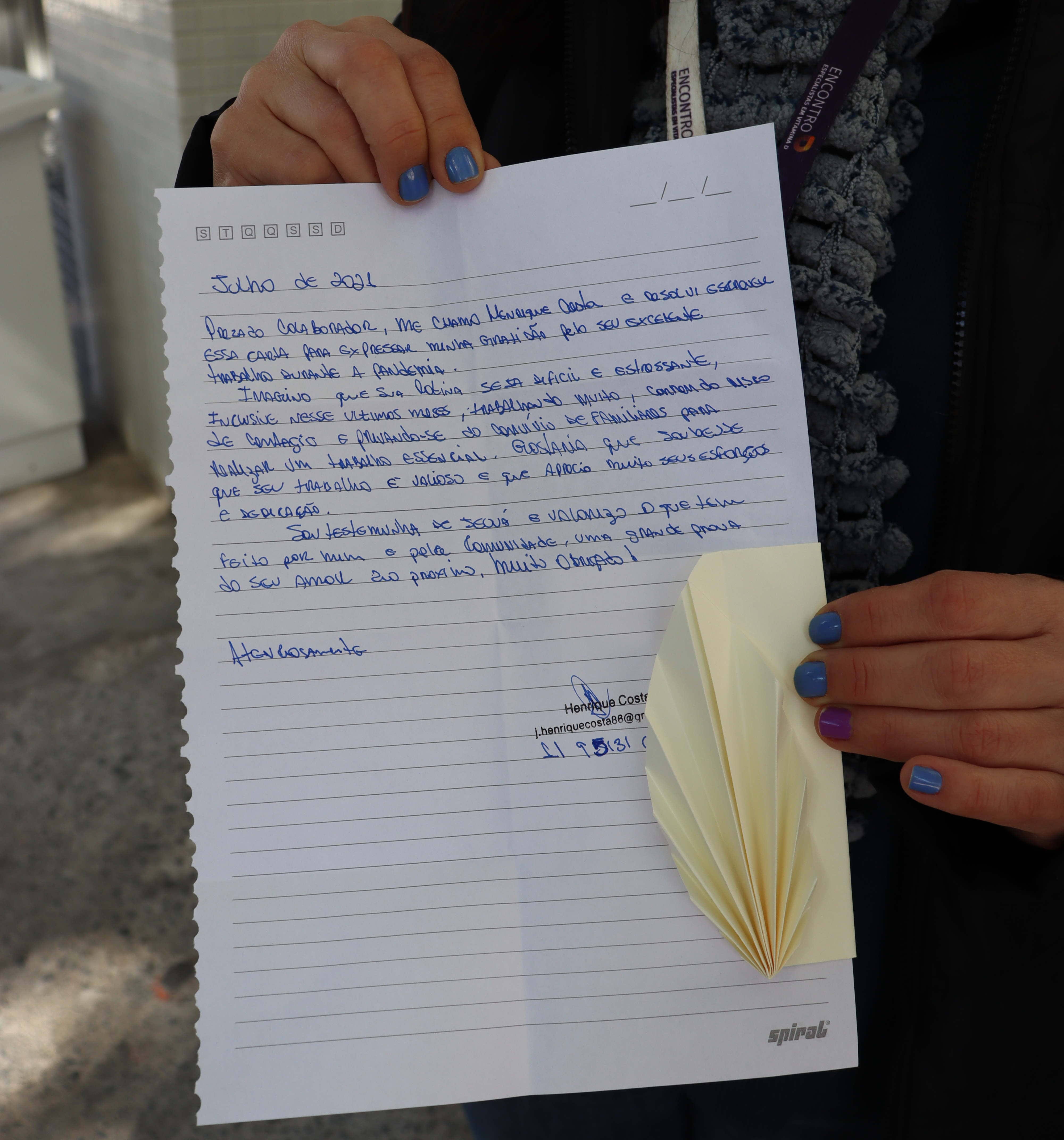 foto de uma mão segurando uma carta escrita em folha branca