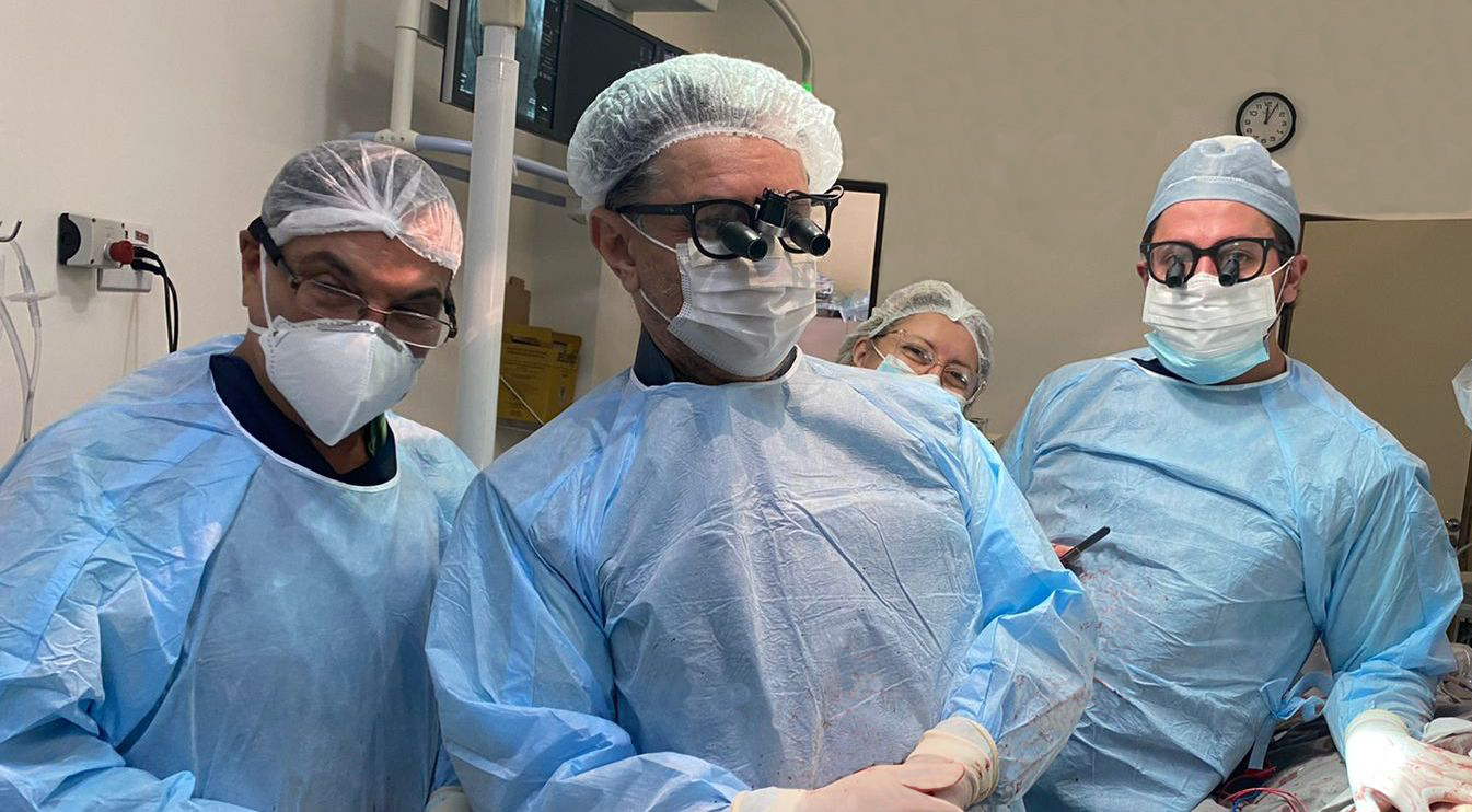 Foto de três médicos e uma médica ao fundo, equipados e fazendo pose para a foto. 