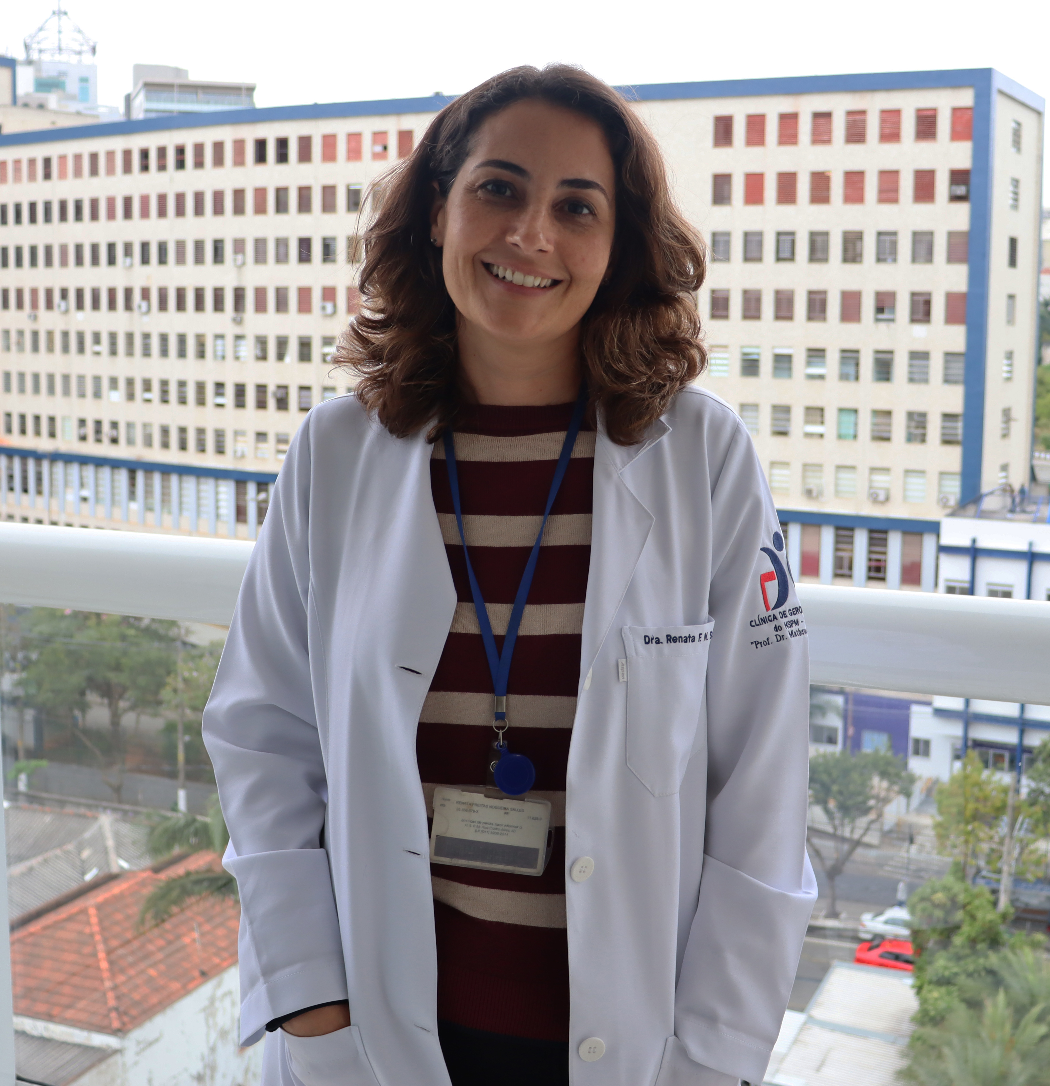 Foto da médica sorrindo com o hospital ao fundo
