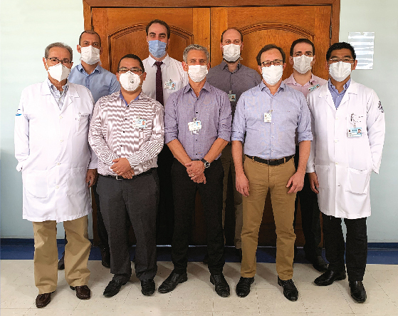 Foto de parte da equipe de urologia, 9 médicos posando em frente a uma porta de madeira.