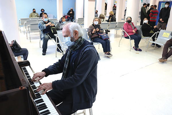 Imagem do saguão do hospital com pianista tocando o piano ao centro 