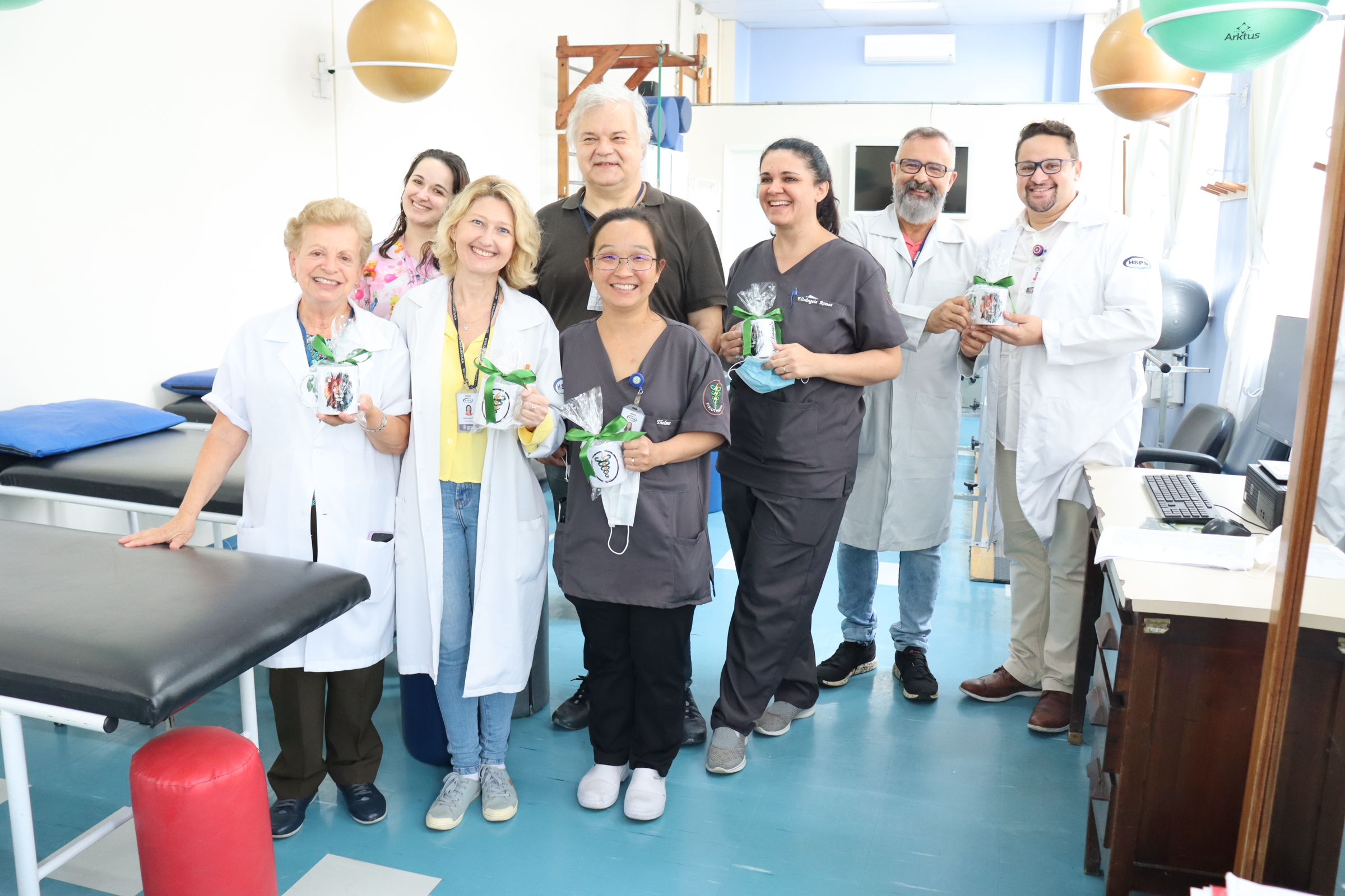 Foto da equipe de 8 fisioterapeutas em grupo em pé, na clínica de Fisioterapia