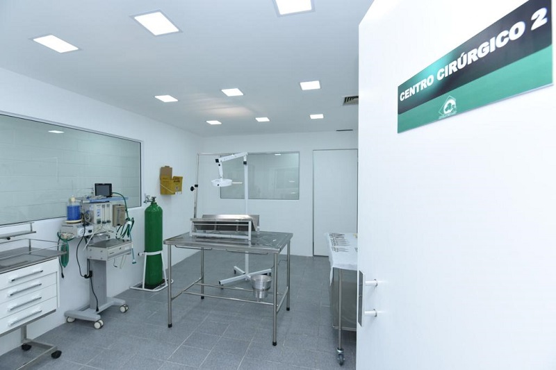 A foto mostra um dos centros cirúrgicos do novo Hospital Veterinário Público com as paredes brancas, uma mesa cirúrgica e equipamentos para realização de cirurgias em cães e gatos