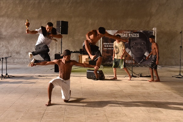 #PraCegoVer: Na imagem, fotografia de cinco indígenas, todos praticando suas danças culturais.