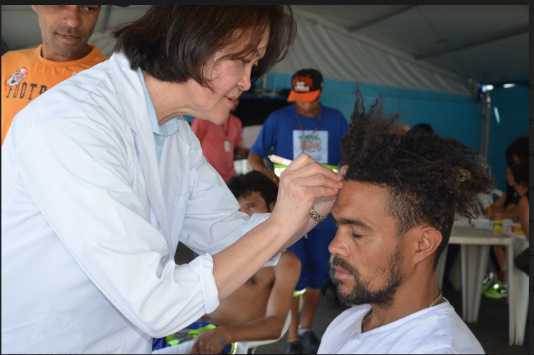 Profissional aplica acupuntura em um homem durante evento no Parque Ibirapuera.