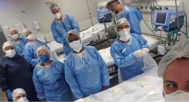 #PraCegoVer: a foto mostra dez profissionais utilizando os equipamentos de proteção individual, numa unidade de terapia intensiva, onde é possível ver três macas e os equipamentos de monitoramento.