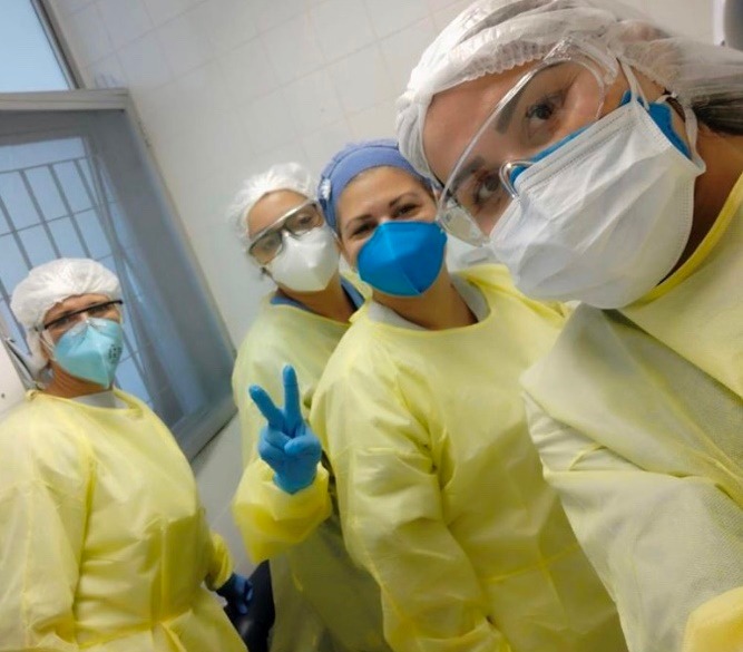  #PraCegoVer: na foto há quatro profissionais de saúde numa sala do hospital, utilizando os equipamentos de proteção individual. 
