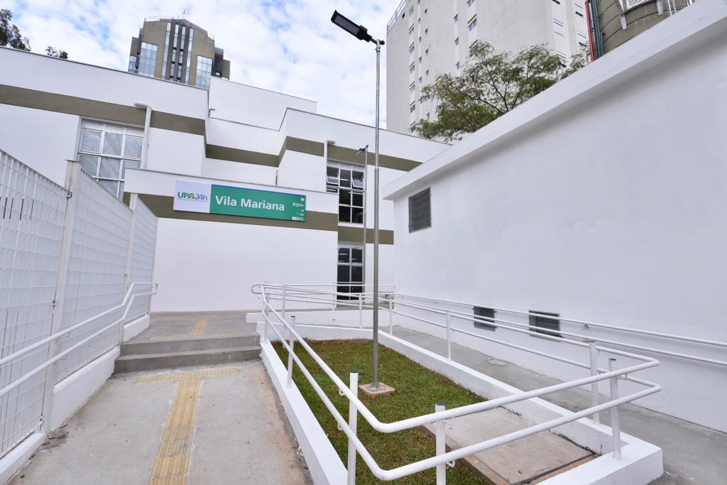 Foto da entrada da UPA Vila Mariana. As paredes são brancas, na fachada há uma placa verde com 