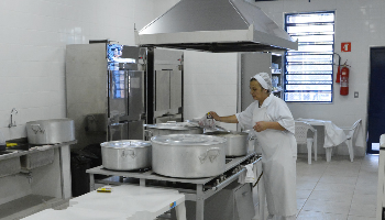 Imagem de uma mulher cozinhando em grandes panelas.