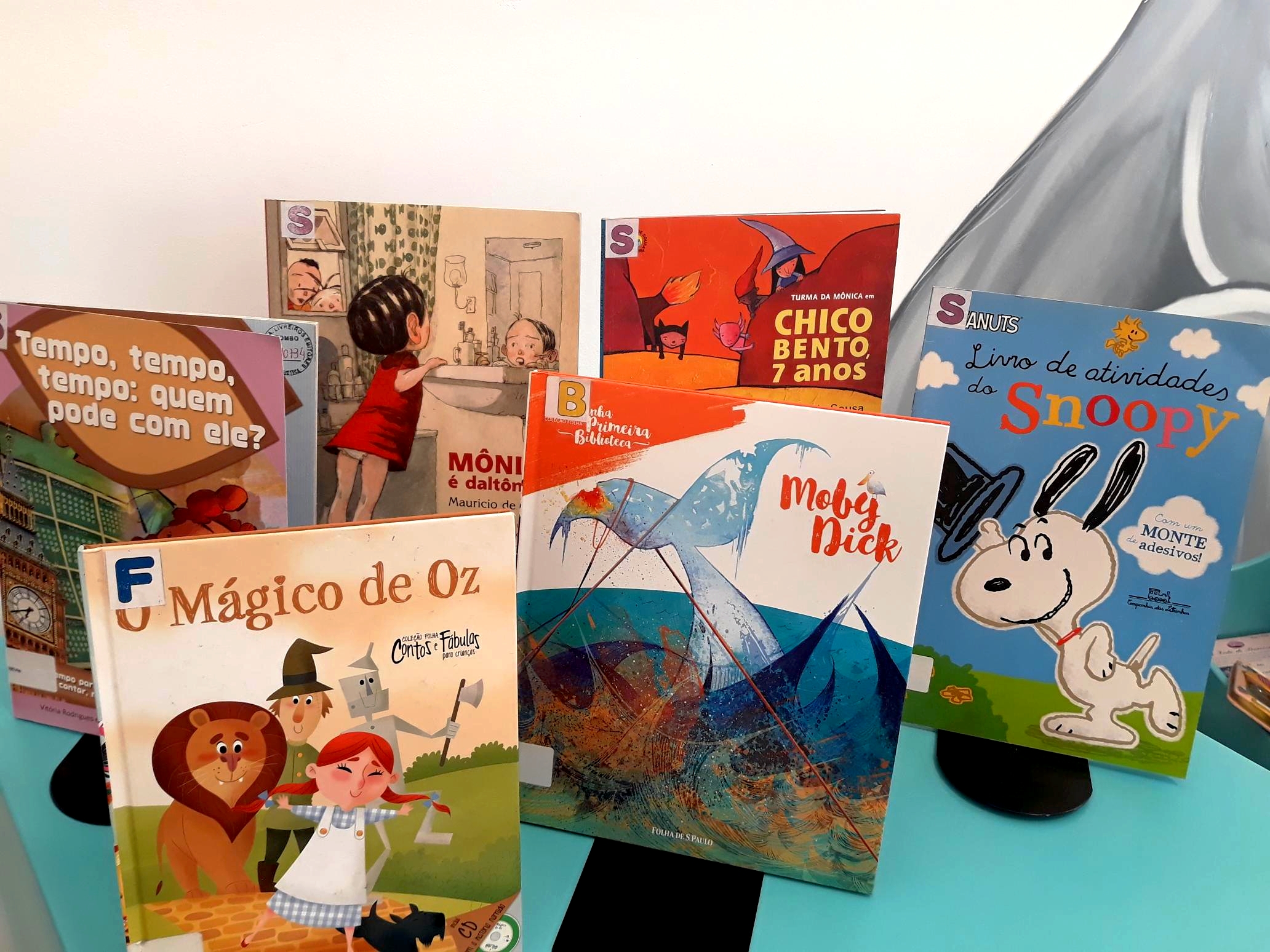 Foto de livros infantis expostos sobre uma mesa azul.