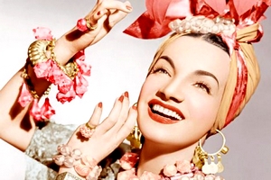 Foto de Carmen Miranda com roupas em tons de rosa; ela sorri
