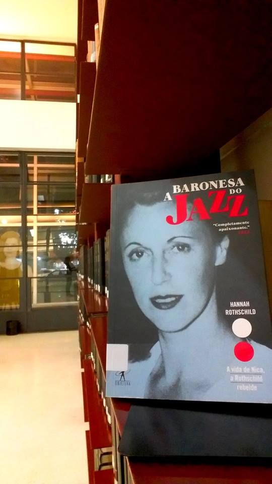Capa do livro com foto em tom azul, de Pannonica de Koenigswarte, tia-avó de Hannah Rothschild. Acima, título A baronesa do jazz escrito em branco com letras garrafais, no qual Jazz aparece destacado na cor rosa.