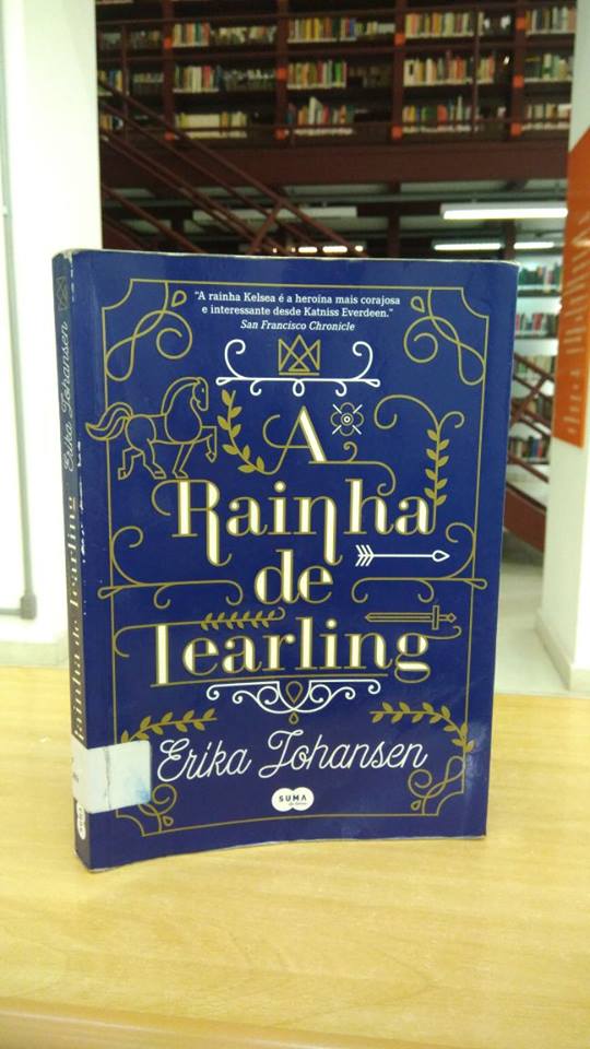 Capa azul marinho com o título escrito em um contorno dourado e preenchimento branco, as letras ligam-se à ilustrações de cavalo, espada, coroa e flores. Abaixo, o nome da autora escrito em branco com letra cursiva.