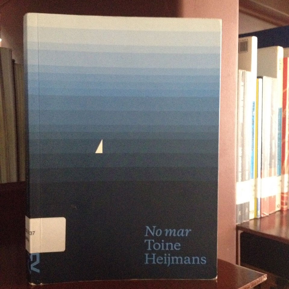 Capa do livro com vários tons de azul. Do lado esquerdo, um triângulo branco que se assemelha a um veleiro e abaixo, do lado direito, está escrito No mar e o nome do autor, Toine Heijmans.