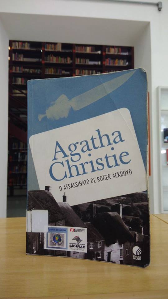 Capa azul com casas cinzas na parte inferior e o nome da autora e do livro sobre um retângulo branco.