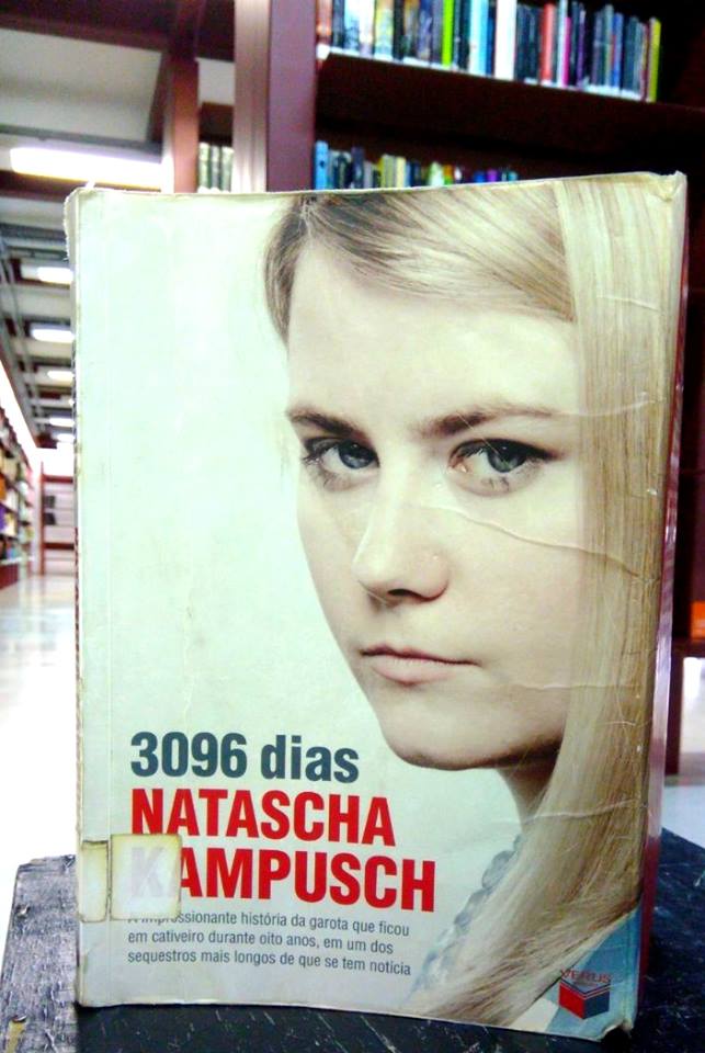 Capa de fundo branco com foto do rosto de Natascha Kampusch do lado direito. Ela é loira e tem olhos claros. Abaixo, do lado esquerdo, o título em cinza seguido pelo nome da autora em vermelho com letras garrafais.