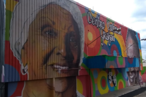 Fachada pintada com graffiti colorido, mostrando o rosto de uma mulher negra com turbante branco