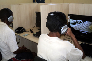 dois jovens assistindo filmes em computadores utilizando headfone.