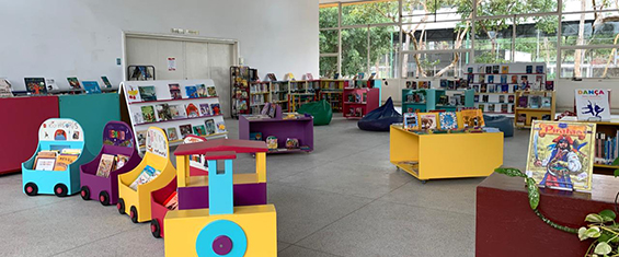 Espaço infantil da Biblioteca Affonso Taunay com as estante, livros coloridos, trenzinho de madeira colorido e caixas de madeira coloridas onde estão inserido livros