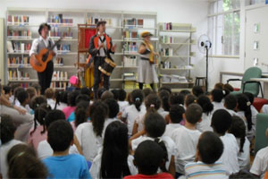 Programação Anne Frank com público sentado nas cadeiras e grupo musical se apresentando no palco