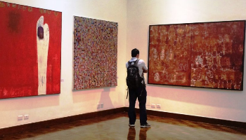 Imagem de um homem observando um quadro do artista plástico Sirón Franco.