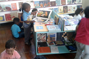 Crianças lendo livros no acervo infantil da biblioteca Viriato Correa