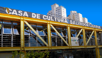 Predio de estruturas de metal amarelas, com uma faixa preta escrito "Casa de Cultura Salvador Ligabue"