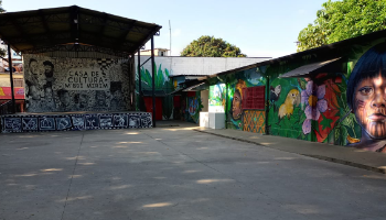 Um pátio cercado por construções térreas decoradas por graffitis.