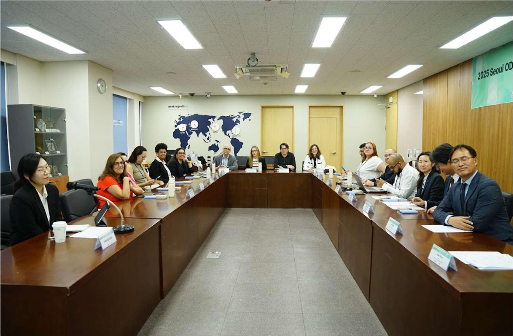 Pessoas reunidas em frente de mesas de madeiras em uma reunião, posadas para a foto. 
